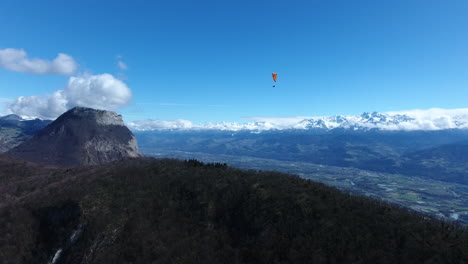 Man-paragliding-over-Grenoble-French-alps-aerial-drone-view